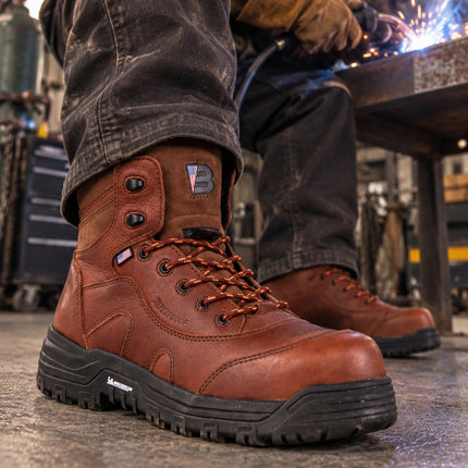Welder wearing copper-brown US Boot Iron Master boots with black Michelin soles in a metal fabrication workshop.